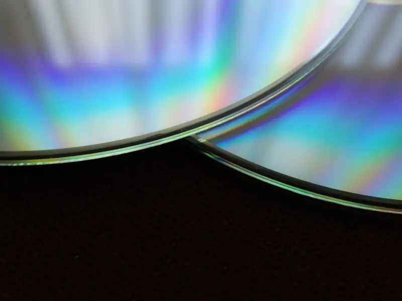 Detailed close-up of two overlapping compact discs showing a colorful rainbow reflection