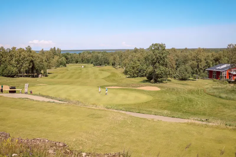 Aerial view of a picturesque golf course with players, surrounded by lush greenery