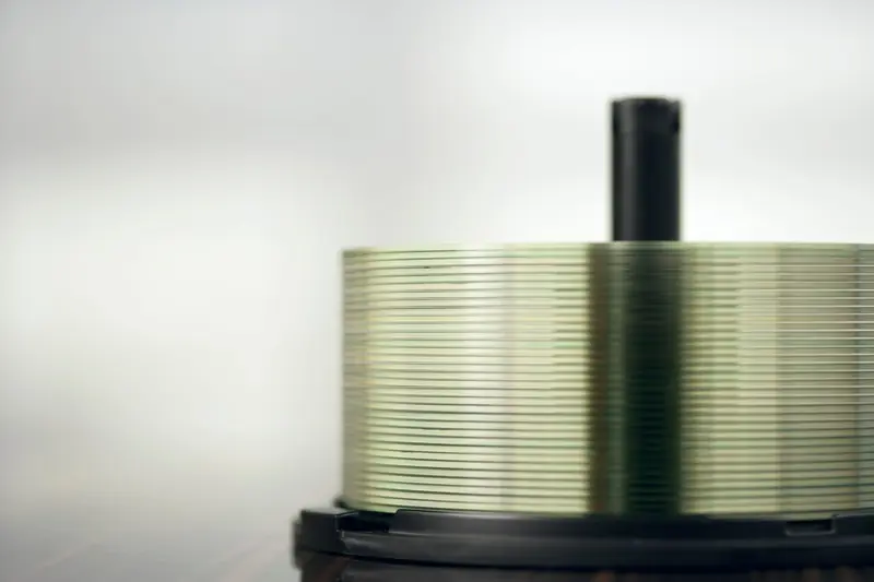 Detailed view of a stack of compact discs on a spindle, highlighting their reflective surfaces