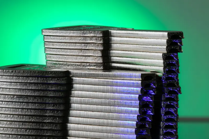 Close-up of stacked metallic discs reflecting green and blue light