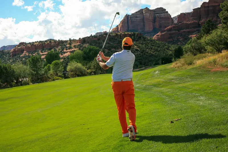 Golfer swinging on a picturesque hillside golf course with vibrant landscape
