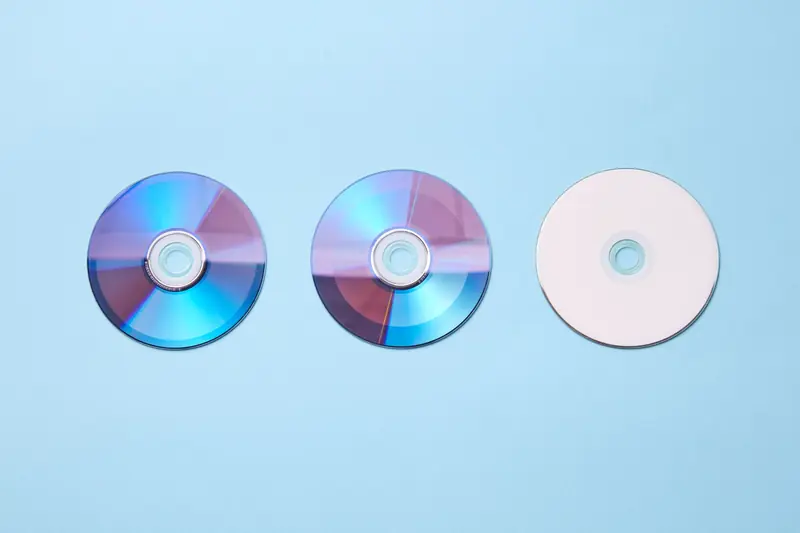 Three classic compact discs with a nostalgic tone on a pastel blue background