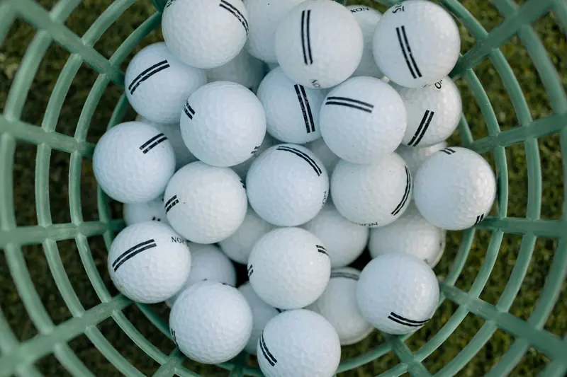 A high-angle view of golf balls in a basket on grass, illustrating golfing equipment
