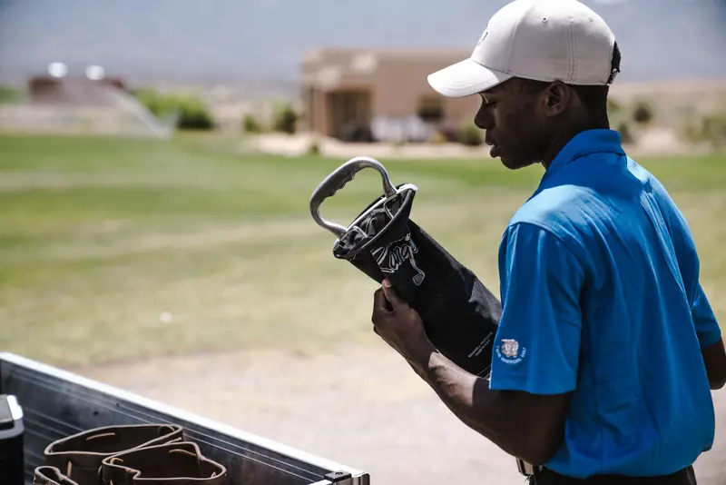 Man organizing golf clubs on a sunny day at a golf course, showcasing outdoor sports equipment
